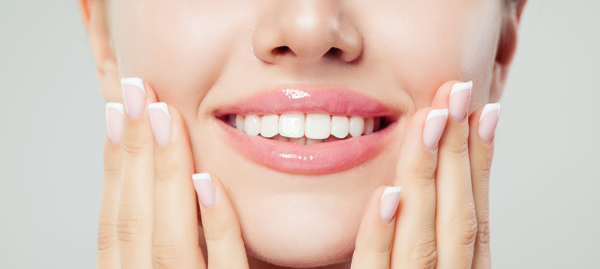 The image shows a person with their mouth open, displaying straight white teeth and a clear complexion, looking directly at the camera.