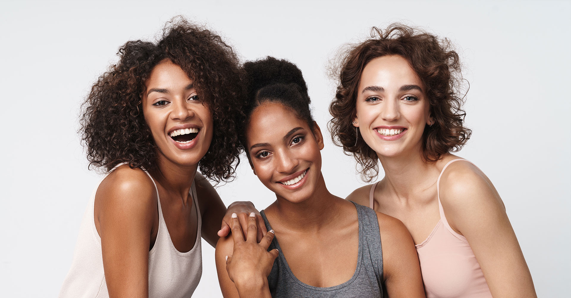 Three women posing together, smiling and looking at the camera.